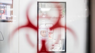 Eine Frau im Schutzanzug arbeitet in einem Hochsicherheitslabor (Symbolbild)