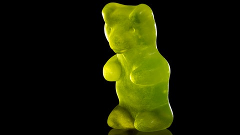 Ein grünes Gummibärchen vor schwarzem Hintergrund
