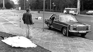 Der Tatort mit den zugedeckten Leichen von Siegfried Buback (vorne links) und seines Fahrers.
