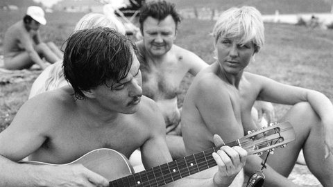 Ein Mann spielt um 1980 an einem FKK-Strand bei Leipzig Gitarre, eine Frau und ein weiterer Mann hören zu: In der DDR gehörte das Nacktbaden zum Mainstream, allerdings waren die Menschen dafür nicht zwangsläufig Mitglied in einem Verein
