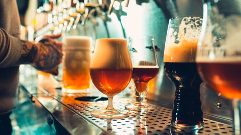 Verschiedene gefüllte Biergläser an einer Theke: Mit neuen Braumethoden, ausgefallenen Geschmacksvarianten und hippem Marketing wollen kleine Craft Beer-Brauereien neue Kunden locken