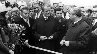 Bundesverkehrsminister Georg Leber (vorne rechts) und Bundeskanzler Willy Brandt (Mitte) übergeben am 25. Oktober 1971 die Sauerland-Linie, ein Autobahnteilstück zwischen Lüdenscheid und Freudenberg, dem Verkehr. Auf einer 189 km langen Strecke vom Ruhrgebiet in den Süden sollte der Verkehr rollen ud damit die Autobahnstrecke nach Köln entlasten.