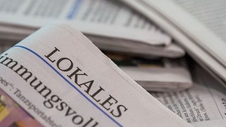 Eine Lokalzeitung wird über andere Zeitungen gehalten