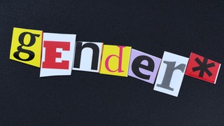 Gendersternchen auf schwarzem Untergrund: "gender" in bunten Buchstaben ausgeschrieben, dahinter ein Sternchen