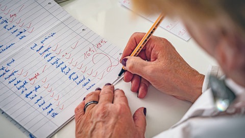 Lehrerin korrigiert Vokabeltest: Eine Bewertung durch Noten ist effizient und schafft rasche Vergleichbarkeit. Es gibt aber Kritik am Notensystem: Es fehle an Objektivität, Stimmungen der Lehrenden können in die Beurteilung einfließen und Noten verleiteten dazu, für Klausuren und Tests Wissen zu pauken, ohne Inhalte wirklich zu durchdringen und zu verstehen.