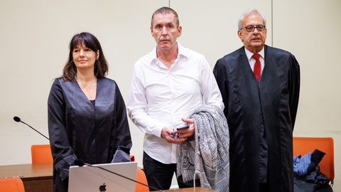 Manfred Genditzki saß 13 Jahre im Gefängnis. Hier steht er im April 2023 vor Prozessbeginn im Wiederaufnahmeverfahren in einem Gerichtssaal des Landgerichts München I zwischen seinen Rechtsanwälten Regina Rick und Klaus Wittmann. Das Landgericht München II hatte ihn 2010 zu einer lebenslangen Gefängnisstrafe verurteilt. 2022 wurde er aus der Haft entlassen; es gab Zweifel, dass er den Mord tatsächlich begangen hat. Am 7. Juli 2023 wurde er vom Landgericht München freigesprochen.