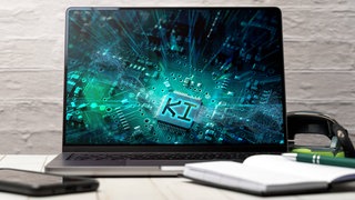 KI steht auf einem Laptop-Bildschirm: KI wird als erstes vor allem die Büroarbeit revolutionieren und Arbeitsplätze überflüssig machen. Doch wie weit kann das gehen – bis zum KI-gestützten Gerichtsprozess?