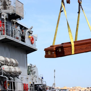 Särge der Flüchtlinge, die beim Unglück am 3. Oktober 2013 vor Lampedusa ums Leben kamen, werden im Hafen auf ein Schiff der italienischen Marine verfrachtet. Das Boot war vor der italienischen Insel mit hunderten Flüchtenden an Bod gesunken, 366 Menschen starben. Das Entsetzen in Europa war groß. Der Papst reiste auf die Insel und rief zu mehr Solidarität mit den Hilfesuchenden auf. Geschehen ist seither das Gegenteil. 