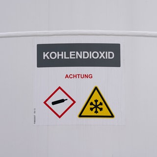 "Kohlendioxid" steht auf einem Tank der neuen Power-to-Liquid-Demonstrationsanlage auf dem Gelände der Raffinerie H&R Ölwerke Schindler GmbH im Hafen. Mit der Anlage sollen aus natürlichen Wasserstoffen und Kohlenstoffdioxid (CO2) nachhaltige Treibstoffe für den Straßen- und Luftverkehr, sogenannte E-Fuels, hergestellt werden.