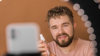 Ein Influencer präsentiert Makeup vor Ringlicht und Smartphone: Auf Instagram, YouTube oder TikTok verbreiten Influencer nicht nur Fotos ihrer Lieblingsessen oder Katzenvideos. Ihre Accounts sind mittlerweile wichtige Verkaufsplattformen geworden. Marken werben mit Follower-starken Accounts für ihre Handtaschen, Sporthosen oder Lippenstift. 