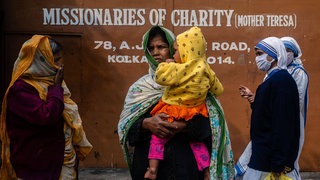 Patienten, die zu einer Gesundheitsuntersuchung bei den "Missionaries of Charity" in Kalkutta, gekommen sind, warten im Dezember 2021 vor dem Tor, während zwei Schwestern an ihnen vorbeigehen. Indiens hindu-nationalistische Regierung schneidet immer mehr christliche, muslimische und andere nicht genehme Hilfsorganisationen von ausländischer Finanzhilfe ab. Seit 2015 haben fast 20.000 NGOs die erforderliche Lizenz verloren.
