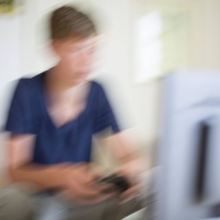 Verschwommenes Bild eines Jungen, der am Computer spielt: Wer kaum stillbare Lust auf Sex verspürt oder fast ununterbrochen Computerspiele spielt, wer besonders lange trauert oder unnütze Dinge hortet, gilt seit 1. Januar 2022 als psychisch krank – gemäß der elften Fassung der internationalen Klassifikation der Krankheiten: ICD-11. 