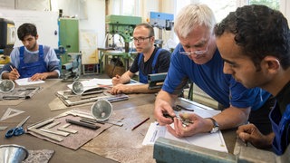 Ausbilder für Metallbearbeitung erklärt einem jungen Flüchtling aus Afghanistan etwas: Trotz Fachkräftemangel bleiben viele Ausbildungsplätze unbesetzt. Individuelle Betreuung kann Azubis mit Startschwierigkeiten helfen, ihren Ausbildungsabschluss zu machen.