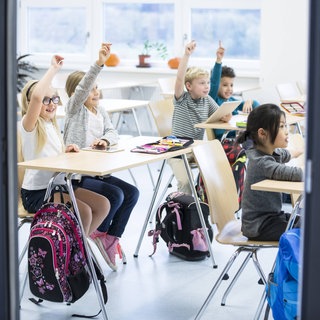 Grundschulkinder beteiligen sich in der Klasse lebhaft am Unterricht: Während die einen die Bewertung durch Noten für motivierend und notwendig halten, finden andere, sie führe in der Schule nur zu kurzfristigem Pauken statt zum nachhaltigen Verstehen. Besser seien individuelle Rückmeldungen statt Ziffernnoten. 