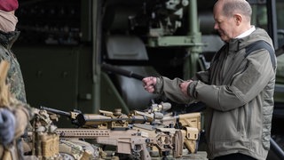 Bundeskanzler Olaf Scholz (SPD) testet während eines Besuchs des Kommandos Spezialkräfte (KSK) der Bundeswehr, wie man eine Waffe hält: 100 Milliarden Euro Sondervermögen hat der Bundeskanzler der Bundeswehr versprochen, um aufzurüsten. Erste Investitionen in teure Waffensysteme sind getätigt. Doch die Ausrüstungsmängel und Nachwuchssorgen sind groß.