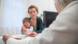 Eine Frau mit ihrem Sohn in einer Kinderarztpraxis. Stefan Pfister ist Kinderonkologe und spricht im Science Talk über die Schwierigkeit der Therapie bei Kindern.