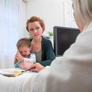 Eine Frau mit ihrem Sohn in einer Kinderarztpraxis. Stefan Pfister ist Kinderonkologe und spricht im Science Talk über die Schwierigkeit der Therapie bei Kindern.