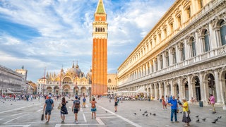 Markusplatz in Venedig: Der massenhafte Tourismus ist ein großes Geschäft und ein riesiges Problem: Souvenirshops und Restaurants verdrängen authentisches Leben, Abfall und Abwasser überlasten die Infrastruktur, Wohnraum wird knapp und die Natur geschädigt. Hotspots wie Venedig suchen nach Lösungen.