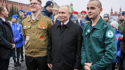 Russlands Präsident Wladimir Putin posiert für ein Foto mit Freiwilligen, Mitgliedern der nationalen russischen Suchbewegung (Poiskovoe dvizhenie) und Kindern gefallener Soldaten der "Sondermilitäroperation" nach einer Blumenniederlegungszeremonie am Minin-und-Poscharski-Denkmal am 4. November 2023 auf dem Roten Platz am Tag der nationalen Einheit Russlands, dem "Tag der Einheit des Volkes": Auch nach zwei Jahren und trotz großer Verluste befürwortet die Mehrheit in Russland den Krieg gegen die Ukraine. Der Rückhalt für den Kreml und Putin hat historische Gründe.