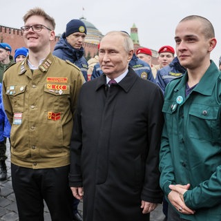 Russlands Präsident Wladimir Putin posiert für ein Foto mit Freiwilligen, Mitgliedern der nationalen russischen Suchbewegung (Poiskovoe dvizhenie) und Kindern gefallener Soldaten der "Sondermilitäroperation" nach einer Blumenniederlegungszeremonie am Minin-und-Poscharski-Denkmal am 4. November 2023 auf dem Roten Platz am Tag der nationalen Einheit Russlands, dem "Tag der Einheit des Volkes": Auch nach zwei Jahren und trotz großer Verluste befürwortet die Mehrheit in Russland den Krieg gegen die Ukraine. Der Rückhalt für den Kreml und Putin hat historische Gründe.