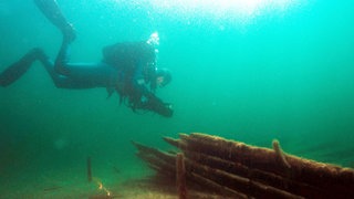 Ein archäologischer Forschungstaucher nähert sich einem Schiffswrack.