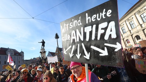 Ein Demonstrant hält im Februar 2024 auf dem Rathausplatz in Augsburg ein Schild mit der Aufschrift "Wir sind heute alle ANTIFA". Mit der Demonstration wollen die Teilnehmer ein Zeichen des Widerstands gegen rechtsextreme Umtriebe setzen.