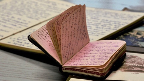 Dicht beschriebenes Tagebuch liegt auf einem Fotoalbum: Erinnerungen festhalten, Bedrückendes loswerden oder einfach Spaß am Schreiben – es gibt viele Gründe, weshalb Menschen Tagebuch schreiben. In der Poesietherapie wird es genutzt, um Probleme und sogar Traumata aufzuarbeiten. (Aufgenommen im Deutschen Tagebucharchiv)