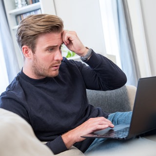 Ein Mann schaut entsetzt auf den Bildschirm seines Notebooks: Psychische Krankheiten sind ein schambesetztes Thema. Im Internet können Betroffene sich niederschwellig informieren oder Hilfe suchen. Das kann Probleme aber auch verstärken oder erst schaffen. 