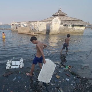 Kinder spielen neben einer überfluteten Moschee, die hinter der Ufermauer im Muara Baru-Gebiet in Jakarta steht. Um die tief liegende Hauptstadt Jakarta vor dem Untergang im Meer zu bewahren, hatte Indonesiens Präsident Joko Widodo den Bau einer riesigen Ufermauer angeordnet