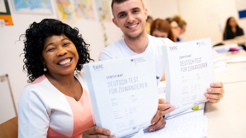 Angela Nwaubani aus Nigeria und Enver Latifi aus dem Kosovo freuen sich über ihre Zertifikate "Deutsch-Test für Zuwanderer", die sie für die erfolgreiche Teilnahme an einem Integrationskurs für Zuwanderer des Bundesamtes für Migration (BAMF) bekommen haben. Die deutsche Sprache gilt in Deutschland als Schlüssel zu einer erfolgreichen Integration. Deshalb hat die Bundesregierung 2005 die staatlich geförderten Integrationskurse eingeführt. 