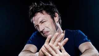 Mann hält mit angeekeltem Gesicht abwehrend die Hände vor sich: Ekel ist ein uralter Schutzmechanismus. Die körperlichen Reaktionen sind überall gleich – und doch ist vieles, was uns ekelt, kulturell erlernt. 