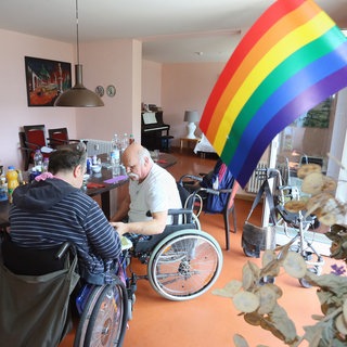 Eine Regenbogen-Fahne schmückt 2015 den Gemeinschaftsraum der Wohngemeinschaft für homosexuelle Senioren in Berlin, die sich zum Mittagessen versammelt haben. Die WG im Berliner "Lebensort Vielfalt" ist eine Pflegeeinrichtungen für Homosexuelle, die sich in herkömmlichen Altenheimen vor Vorurteilen und Diskriminierung fürchten und zurückziehen. Mittlerweile, 2025, gibt es drei Wohnprojekt der Schwulenberatung in Berlin.