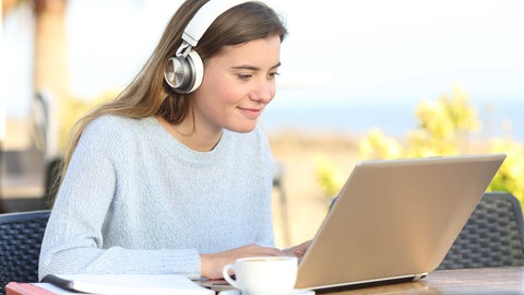 Junge Frau arbeitet am Laptop: Vom heimischen Schreibtisch ins Ausland: Während der Corona-Pandemie fanden viele Kurse an ausländischen Universitäten online statt. Diese Art von Auslandssemester hat durchaus Vorteile: Digitale Kompetenzen und interkulturelle Vernetzung werden gefördert – ein Pluspunkt für viele Arbeitgebende.