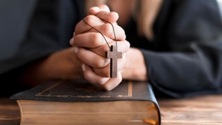 Betende Person mit Kreuz und Bibel: Christlicher Fundamentalismus ist vielschichtig und überkonfessionell. Es gibt Verbindungen zu rechts-konservativen Vertretern der Kirche und des Adels, aber auch zur extremen Rechten. Er ist in großen Teilen antifeministisch, antimuslimisch und antisemitisch. 