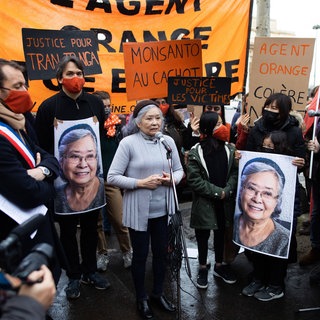 Die Aktivistin Tran Tho Nga 2021 bei einem Protest in Paris: Tran Tho Nga arbeitete als Journalistin für Nordvietnam. Unterwegs in den Süden geriet sie mehrmals in den Giftregen. Im Dschungel kam ihre erste Tochter zur Welt. Mit 17 Monaten starb die kleine Viet-Hai an einem schweren Herzfehler. Später wurde Tran Tho Nga verhaftet. Im Gefängnis wurde ihre zweite Tochter geboren, unheilbar krank. Tran Tho Nga hat 14 Firmen verklagt, die damals Agent Orange herstellten. 