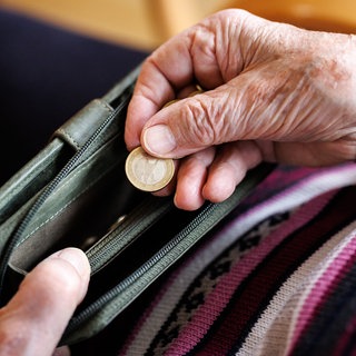 Eine ältere Dame zählt Geldmünzen aus ihrem Portemonnaie ab: Experten sagen, dass die Rentenkatastrophe droht. Das System muss dringend reformiert werden und Beschäftigte müssen stärker als bisher selbst fürs Alter vorsorgen. 