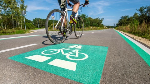 Radschnellweg in Müchen mit grüner Markierung auf dem Boden: Fahrradfahren ist gesund und klimafreundlich – im Alltag aber auch gefährlich und wenig komfortabel. Für stressfreien Fahrspaß braucht es neben sicheren Radwegen auch eine smarte Navigation und mehr Komfort, etwa bei Bahnfahrten.