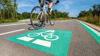 Radschnellweg in Müchen mit grüner Markierung auf dem Boden: Fahrradfahren ist gesund und klimafreundlich – im Alltag aber auch gefährlich und wenig komfortabel. Für stressfreien Fahrspaß braucht es neben sicheren Radwegen auch eine smarte Navigation und mehr Komfort, etwa bei Bahnfahrten.