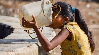 Ein Mädchen in Indien trinkt aus einem Kanister. Der Brunnen ist fast ausgetrocknet: Extremes Wetter wie beispielsweise eine Hitzewelle wirkt sich auf die Gesundheit des Menschen aus. Das Institut für Global Health der Universität Heidelberg untersucht die Folgen von extremem Wetter und entwickelt Präventionsmaßnahmen.