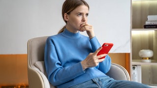 Eine junge Frau hält nachdenklich ihr Smartphone vor sich und grübelt: Grübeln – oder neudeutsch "Overthinking" – ist derzeit ein viel diskutiertes Thema in Selbsthilfebüchern und sozialen Medien. Studien zeigen jedoch, dass gerade die Abhängigkeit von digitalen Geräten das Grübeln verstärkt. Was hilft, klare Gedanken zu fassen?