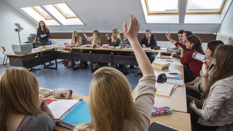 Das Bild zeigt eine Schulklasse im Unterricht. Abitur in acht oder neun Jahren? G8 oder G9 - G8 bedeutet für die Schülerinnen und Sc hüler in der Regel meht Stress..