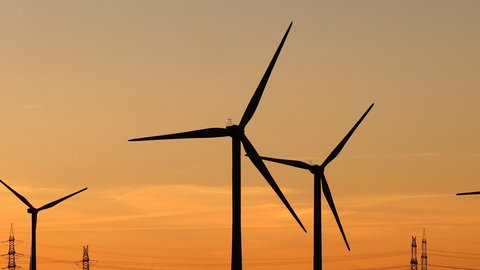 Strommasten und Windräder im Sonnenuntergang
