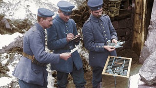 Nachrichtenübermittlung durch Brieftauben im Ersten Weltkrieg bei der deutschen Armee: Soldaten schreiben eine Meldung, die dann mit einer der Brieftauben abgeschickt werden soll (März 1917)