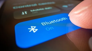 Finger berührt Bluetooth-Symbol auf einem Smartphone: Bluetooth ist eine Funktechnologie. Sie macht es möglich, dass Geräte über kurze Distanzen drahtlos miteinander kommunizieren und Daten auszutauschen.