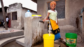 Eine junge Frau holt Wassser an einem Brunnen in der Hauptstadt Dar es Salam