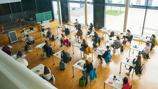 Schüler schreiben Abitur in einer Turnhalle. Einser-Abis werden immer häufiger an Schulen. Der Deutsche Lehrverband befürchtet, dass der Abschluss zu einfach wird.
