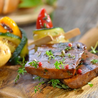 Grillteller mit Seitan dazu Zucchini-Röllchen mit Paprika und Grillkartoffel, mit frischem Ciabattabrot serviert. Symbolfoto.