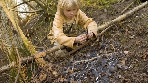 Ein Junge betrachtet die Federn eines Buntspechts, den ein Sperber erbeutet hat: Das Untersuchen von Federn ist kein Problem. Das Sammeln der Federn von Wildvögeln hingegen ist selbst in diesem Fall verboten.