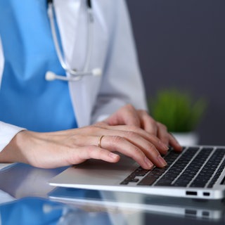Eine Ärztin tippt auf einen Laptop
