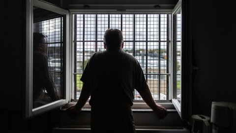 Ein Häftling schaut durch das vergitterte Fenster seiner Zelle: Häftlinge kämpfen mit Süchten, Depressionen, Schuldgefühlen, Ängsten oder Psychosen. Die Suizidrate ist deutlich höher als bei Menschen außerhalb des Strafvollzugs.